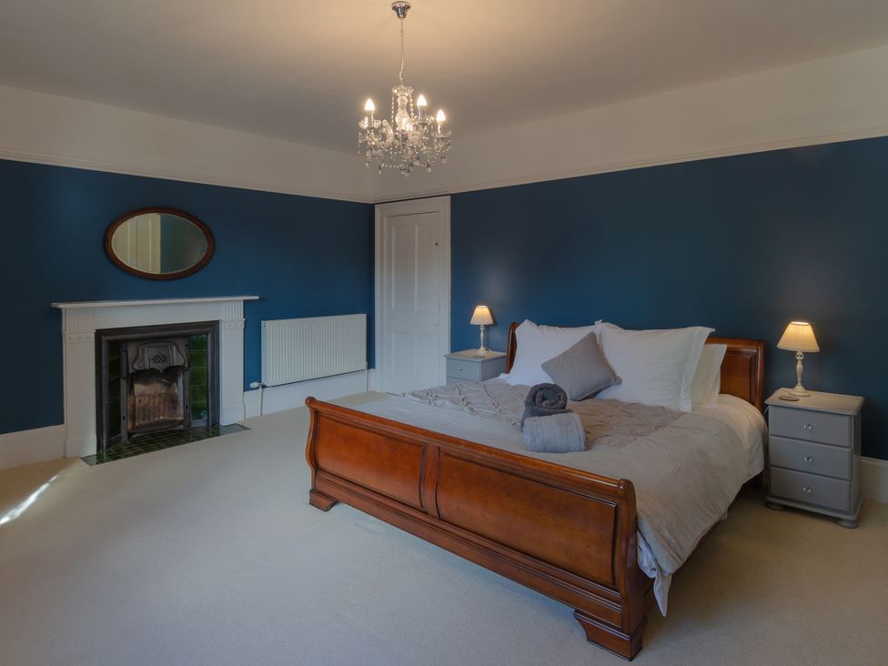 A bedroom with a bed and nightstands at Badminton Farm Cottage in Acton Turville
