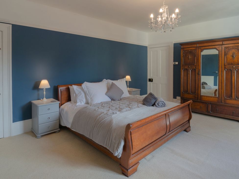 A bedroom with a bed and wardrobe at Badminton Farm Cottage Acton Turville