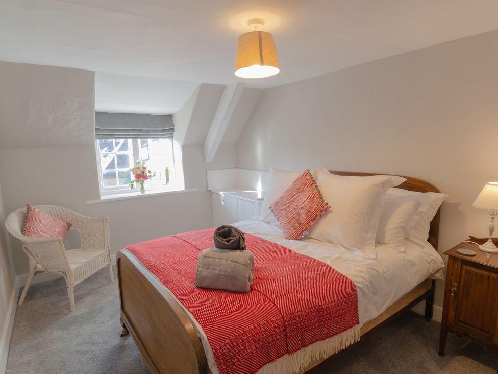 A bedroom with a bed and a chair at Badminton Farm Cottage in Acton Turville