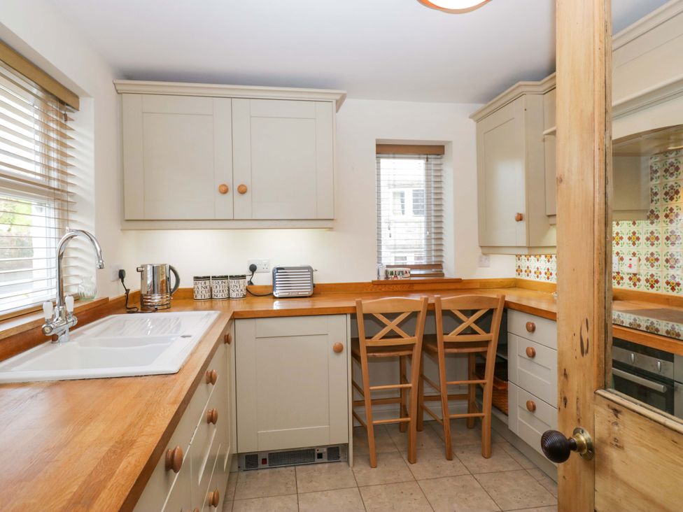 A kitchen with a sink, countertop, bar stools at 11 Tram Lane Kirkby Lonsdale