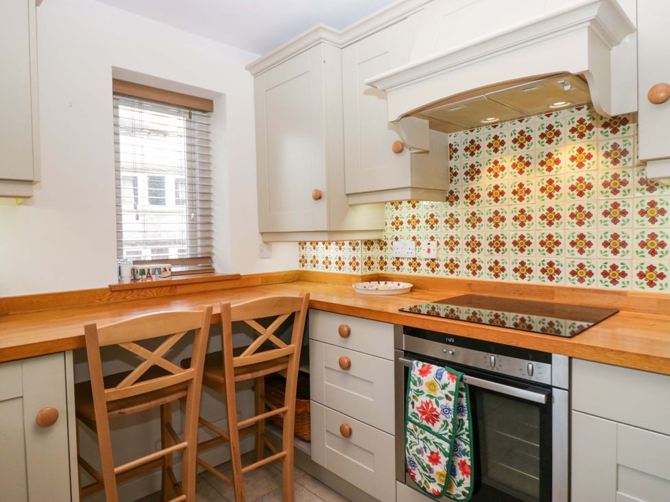 A kitchen with cabinets and bar stools at 11 Tram Lane in Kirkby Lonsdale