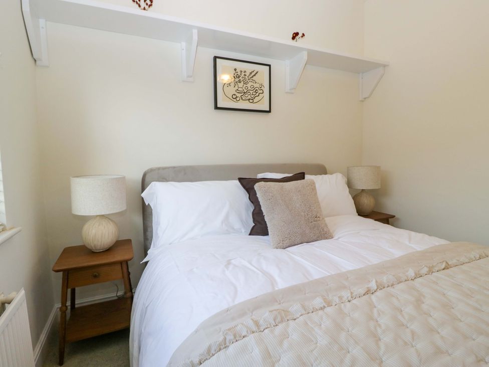 A bedroom with a bed, bedside table and lamps at 11 Tram Lane in Kirkby Lonsdale