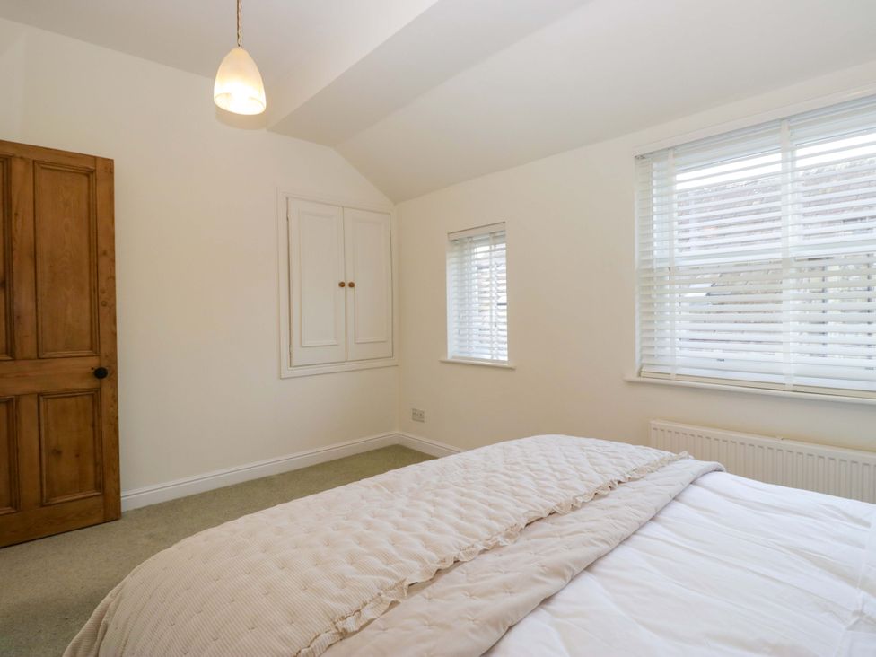 A bedroom with a bed, door, windows, and storage at 11 Tram Lane, Kirkby Lonsdale
