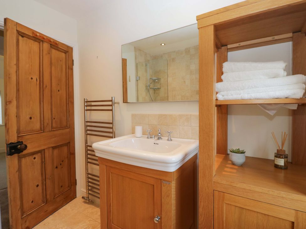 A bathroom with a sink, towel rack, and shelves at 11 Tram Lane in Kirkby Lonsdale