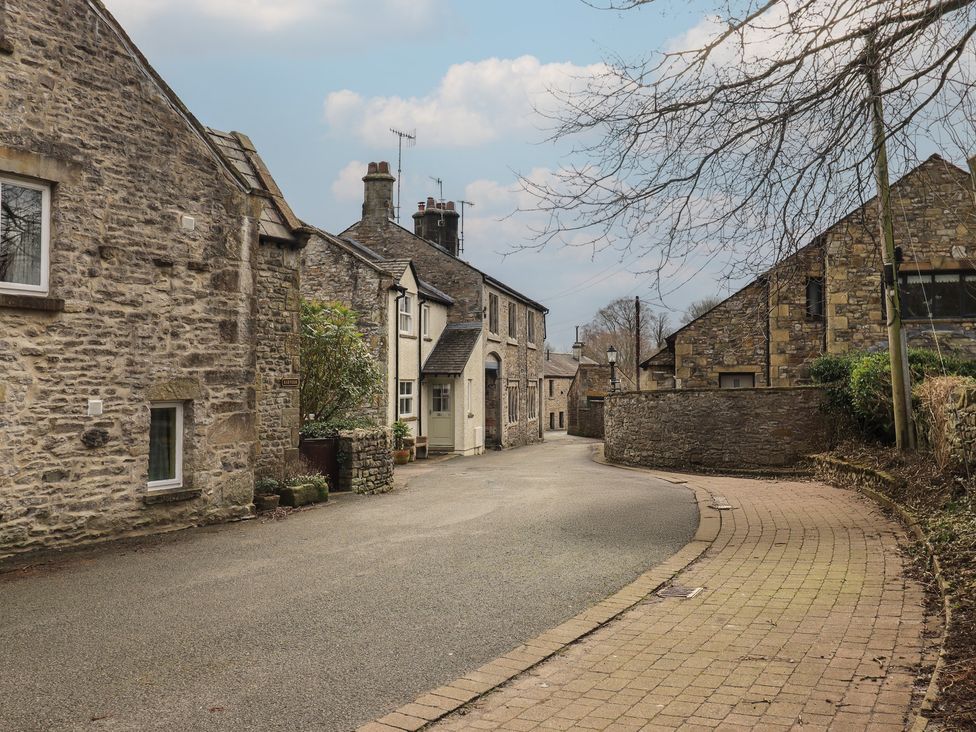 A street with stone buildings and trees at Tram Lane Cottage in Kirkby Lonsdale
