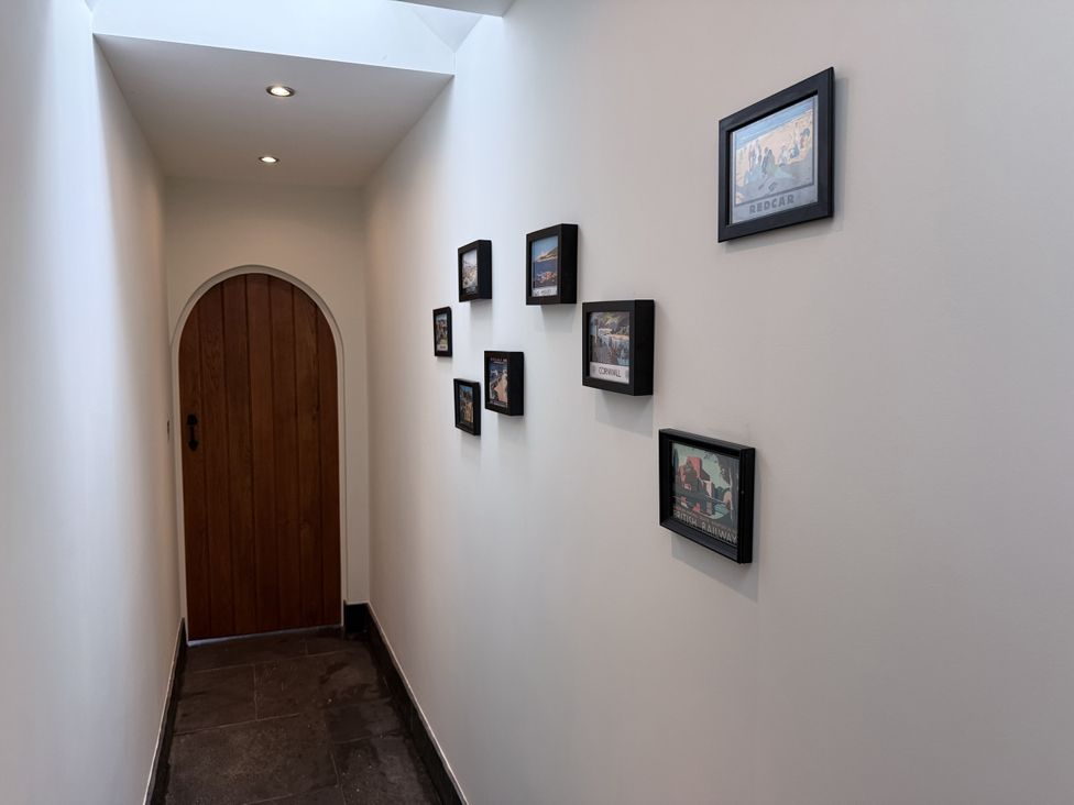 A hallway with a wooden door and framed pictures at New House Barn Ashbourne