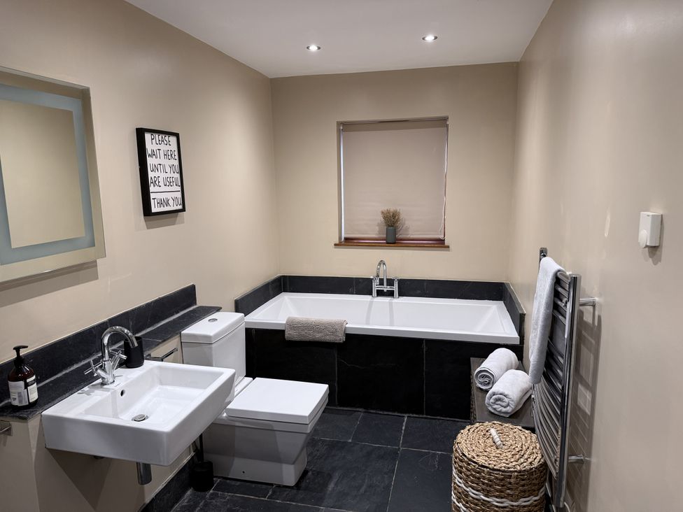 A bathroom with a bath tub, sink, toilet and mirror at New House Barn in Ashbourne