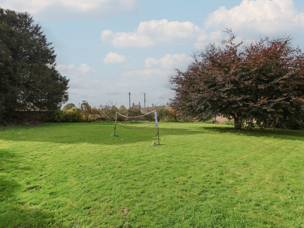 A garden with a badminton net and a tree at The Old Dairy in Acton Turville near Nettleton