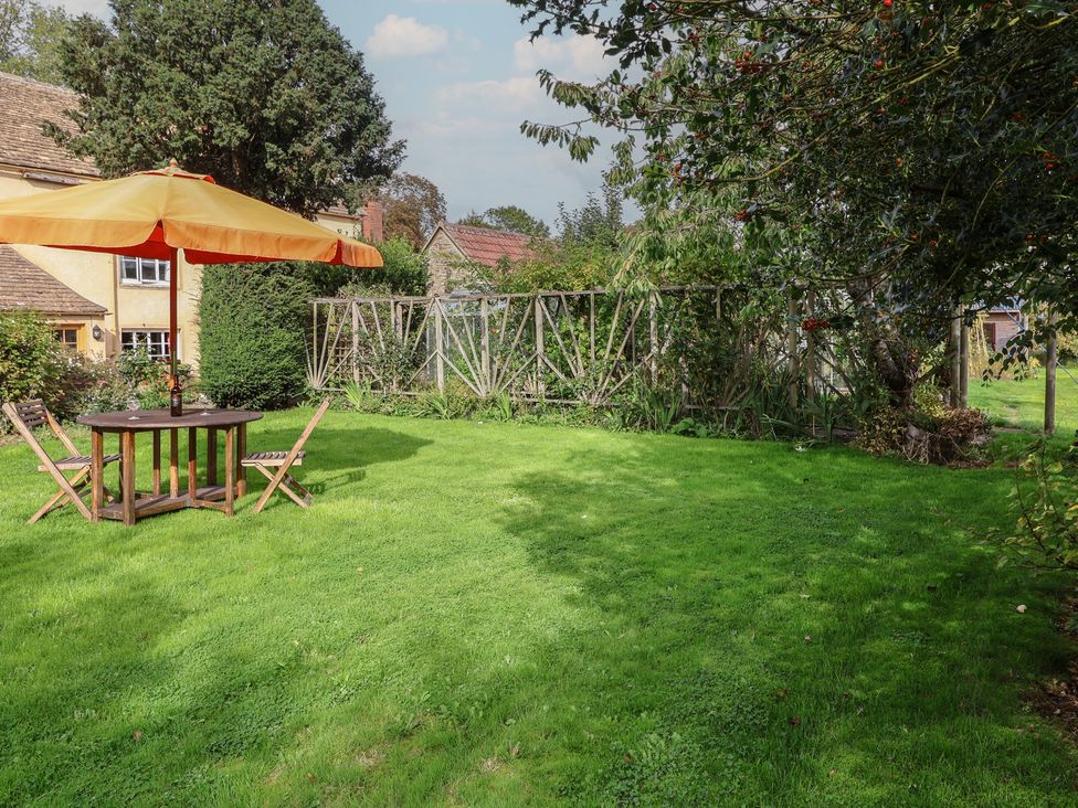 A garden with a table and umbrella at The Old Dairy Acton Turville near Nettleton
