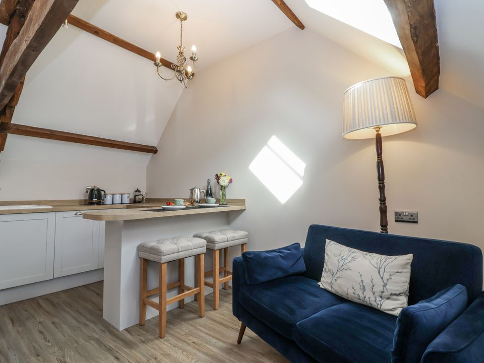 A living room with a kitchen counter and bar stools at The Old Dairy in Acton Turville near Nettleton