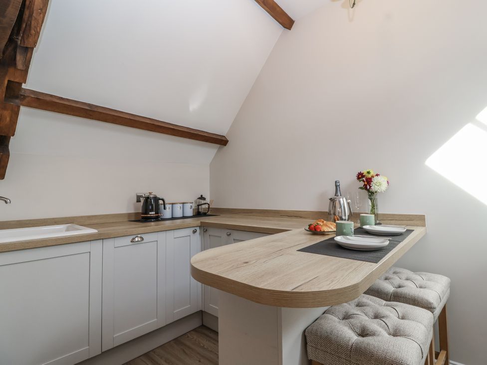 A kitchen with a counter and bar stools at The Old Dairy Acton Turville near Nettleton