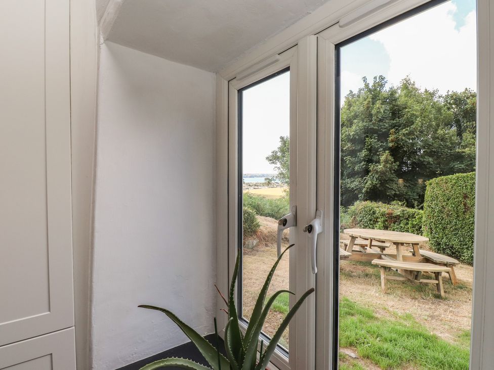 A window with a plant overlooking a garden with seating at Garreg Fawr 