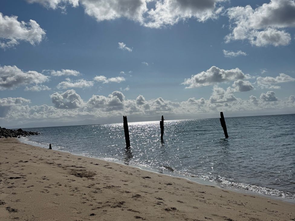 A beach with wooden posts in the water at Garreg Fawr in Llanbedrog