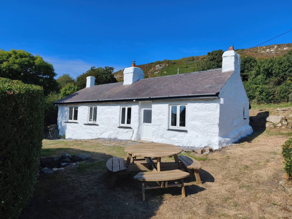 A cottage with a table and chairs outside at Garreg Fawr in Llanbedrog