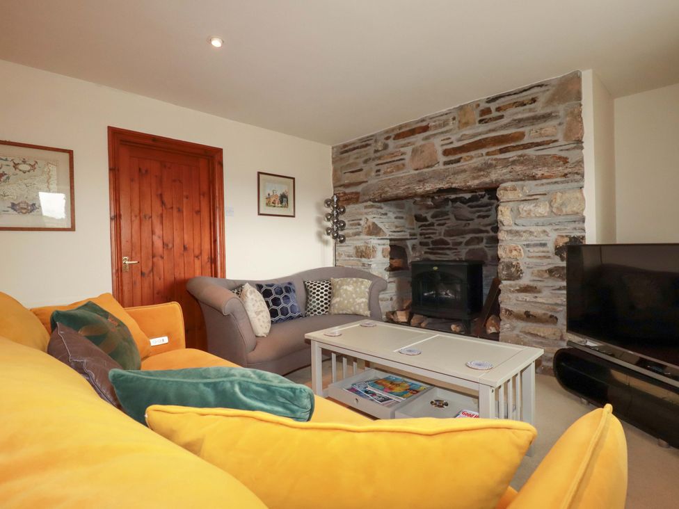 A living room with a sofa and a fireplace at Rosewin Farmhouse near St Minver
