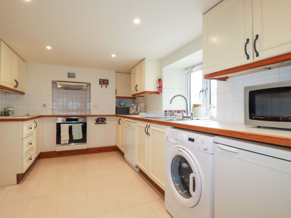 A kitchen with cabinets, oven, sink, and appliances at Rosewin Farmhouse near St Minver
