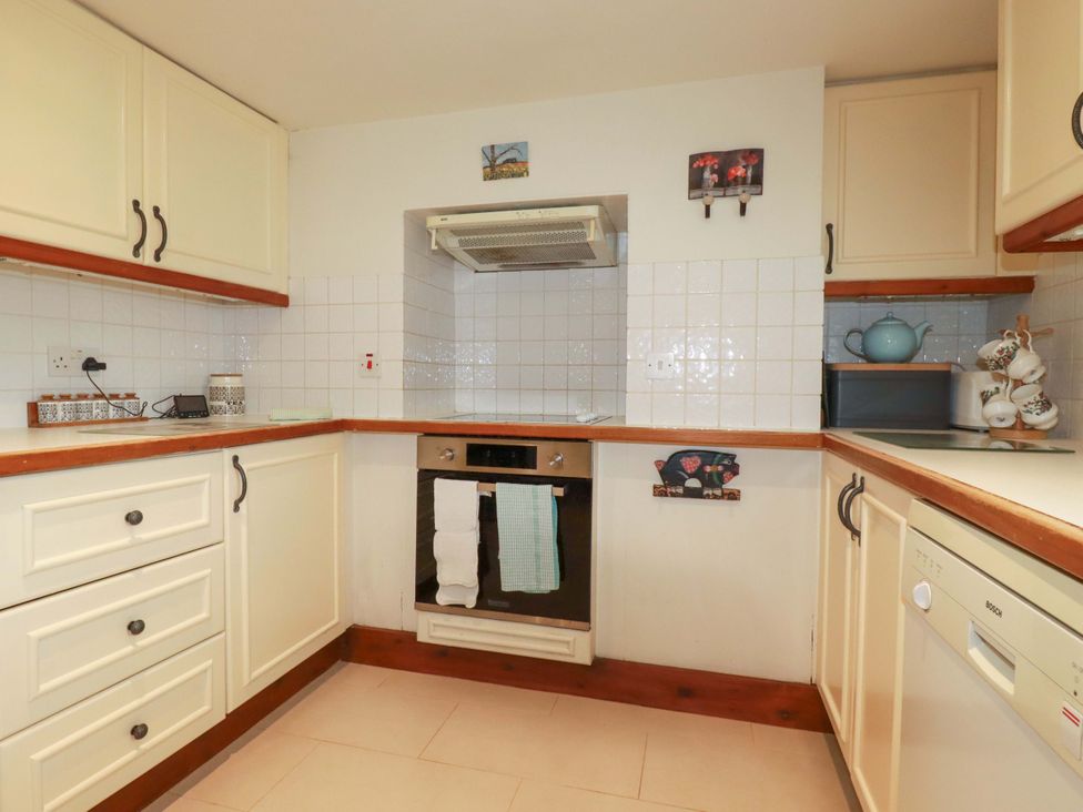 A kitchen with cabinets, stove, sink, and dishwasher at Rosewin Farmhouse near St Minver