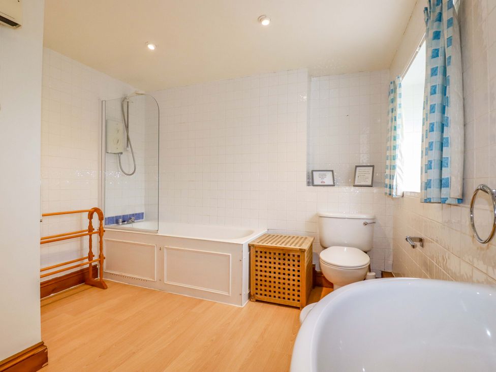 A bathroom with a bathtub, toilet, and shower at Rosewin Farmhouse near St Minver