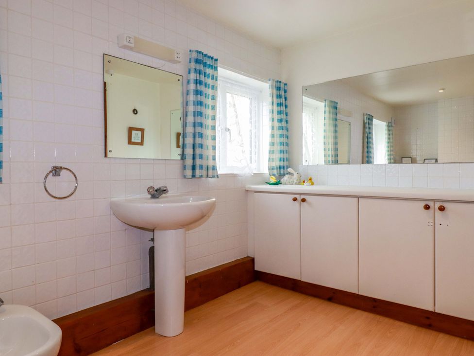 A bathroom with a sink, mirror, and toilet at Rosewin Farmhouse near St Minver
