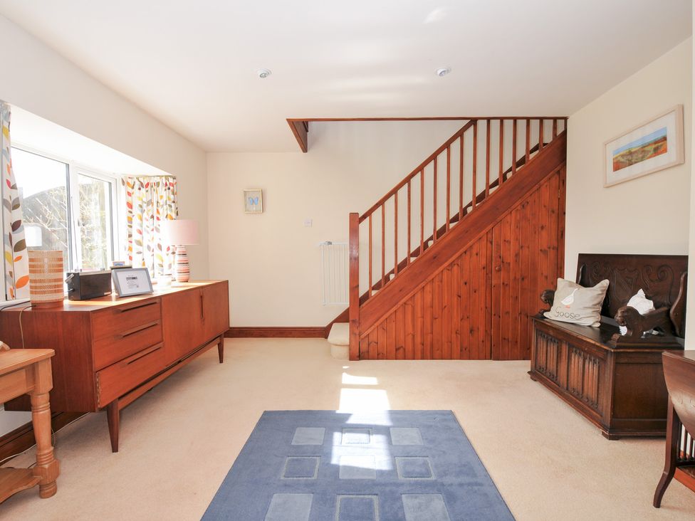 A living room with a sideboard and staircase at Rosewin Farmhouse near St Minver