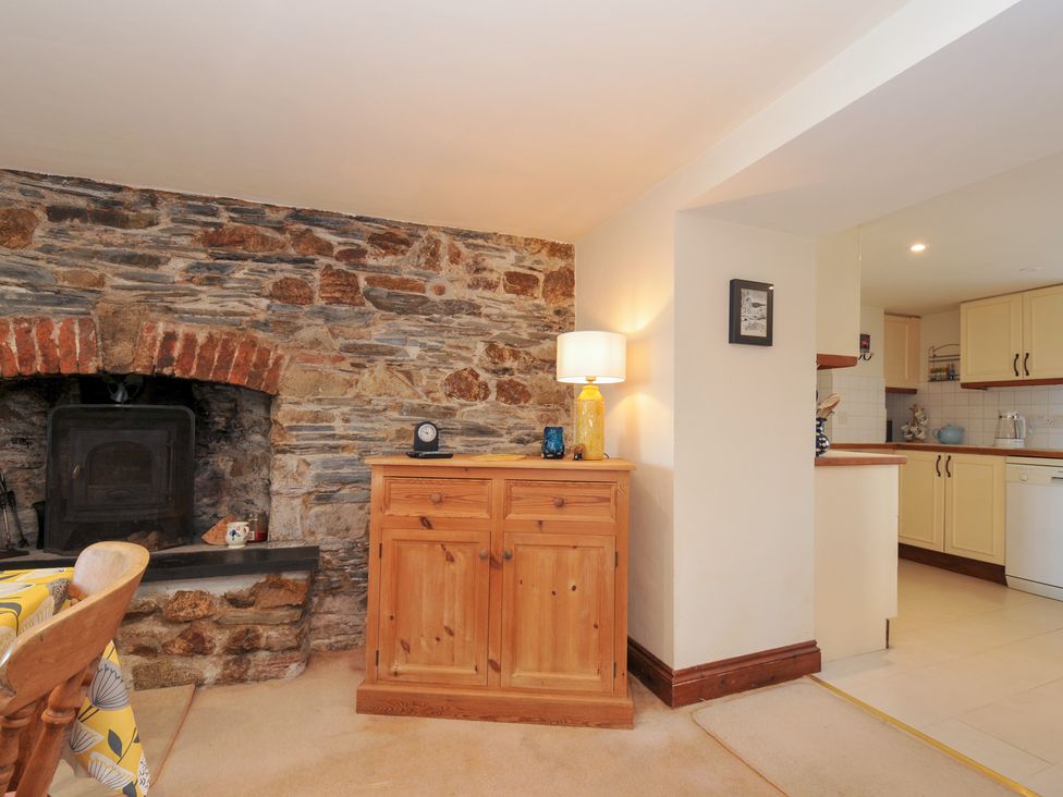 A living room with a fireplace and cabinet at Rosewin Farmhouse near St Minver