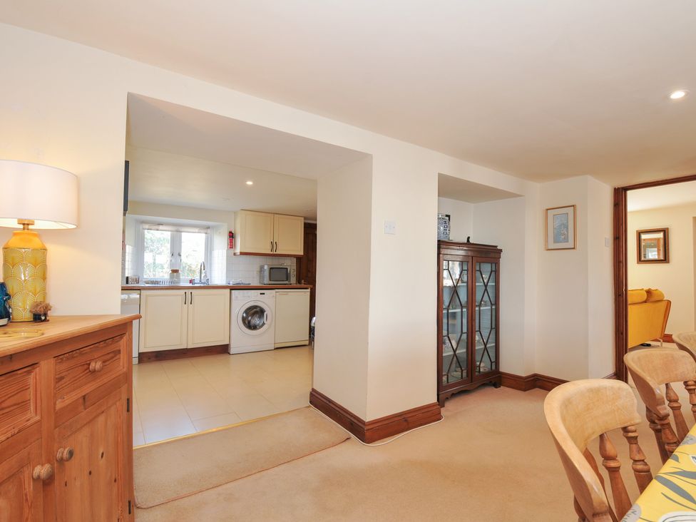 A dining room with a sideboard and a view into the kitchen at Rosewin Farmhouse near St Minver