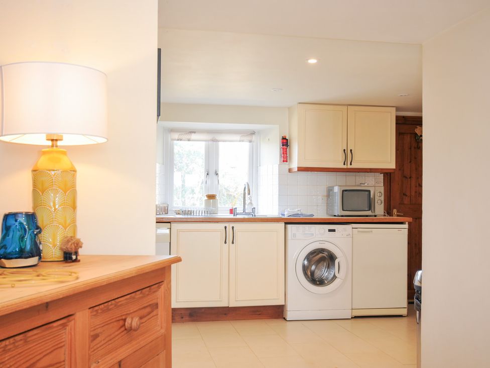 A kitchen with cabinetry, a washing machine, and a microwave at Rosewin Farmhouse near St Minver