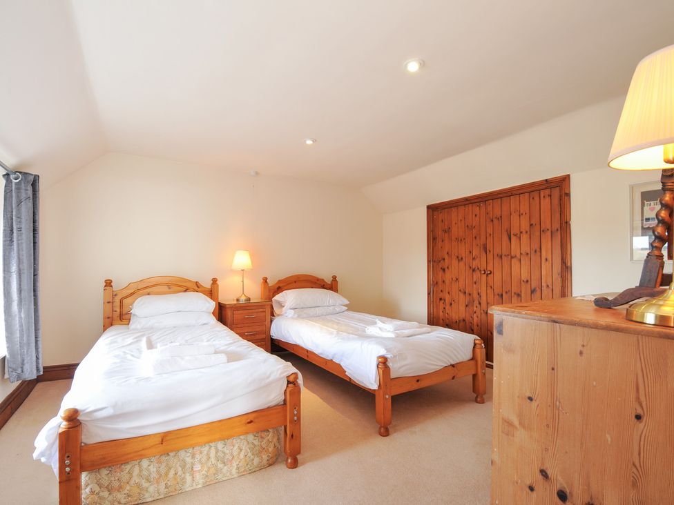 A bedroom with two single beds and a bedside table at Rosewin Farmhouse near St Minver