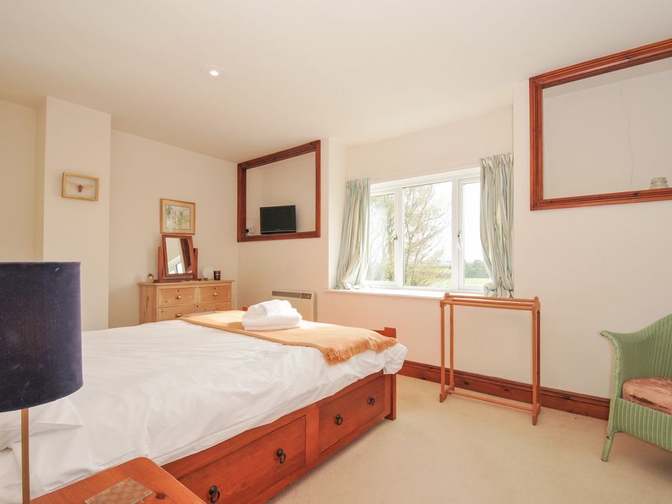 A bedroom with a bed, dresser, and television at Rosewin Farmhouse near St Minver