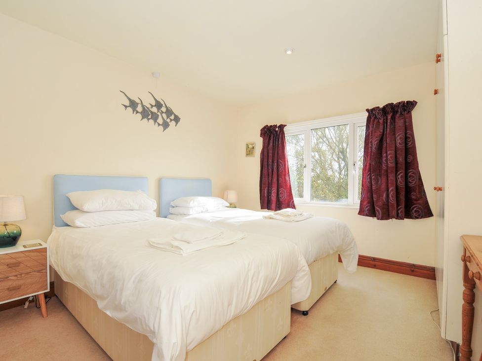 A bedroom with two beds and a window at Rosewin Farmhouse near St Minver