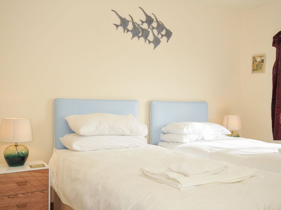 A bedroom with two beds and a bedside lamp at Rosewin Farmhouse near St Minver
