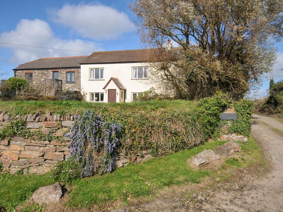 A house with a stone wall and trees at Rosewin Farmhouse near St Minver