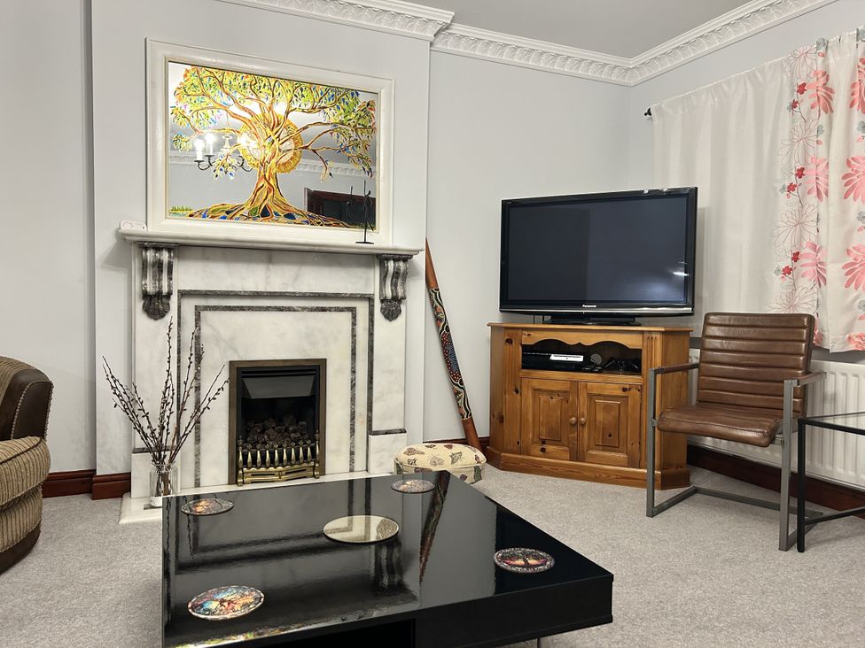 A living room with a fireplace and a television at The Peak View Holmfirth