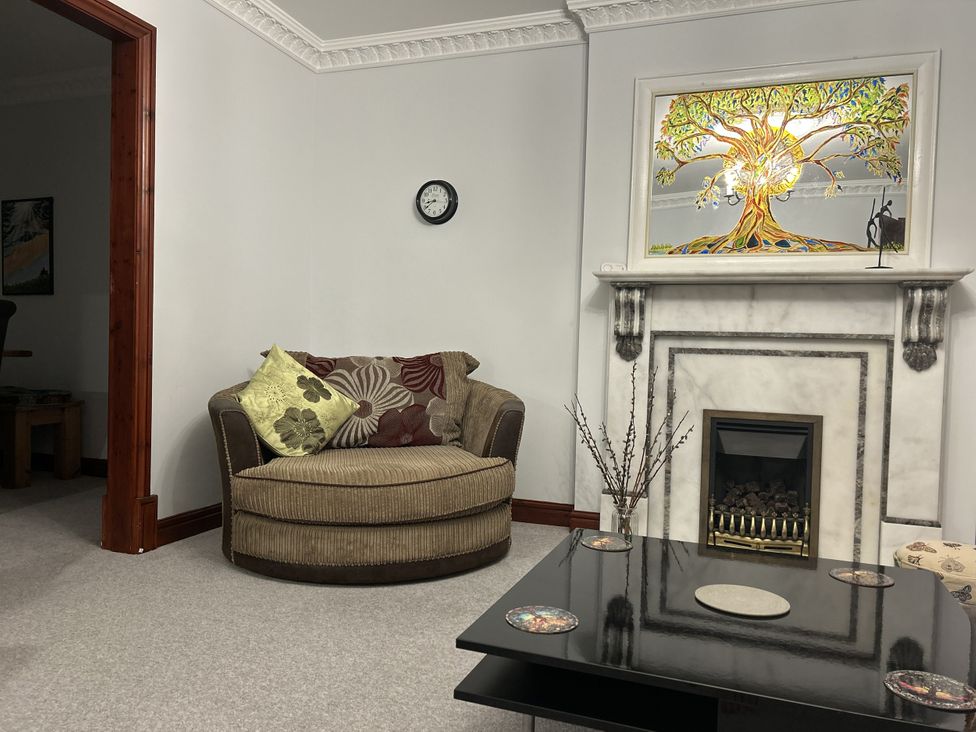 A living room with a sofa, fireplace, clock and painting at The Peak View Holmfirth