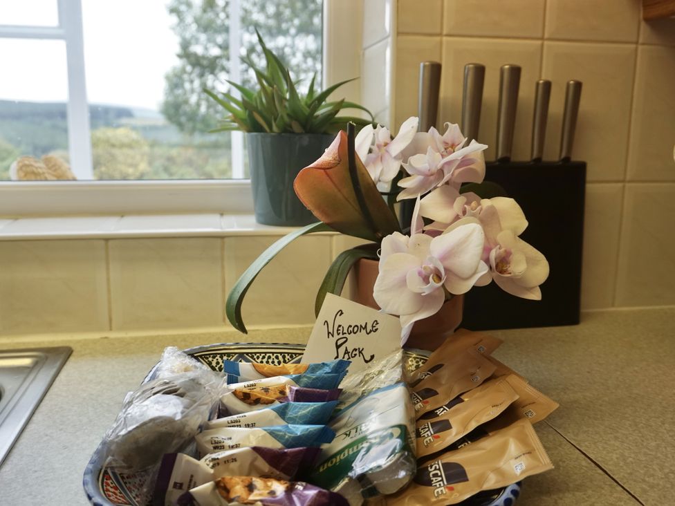 A kitchen countertop with a bowl of snacks and flowers at The Peak View Holmfirth
