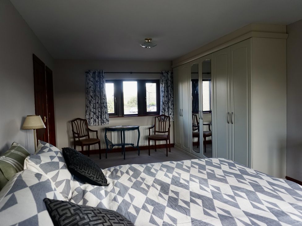 A bedroom with a bed, wardrobe, chairs, and a table at The Peak View Holmfirth