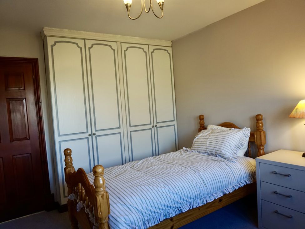 A bedroom with a bed, wardrobe, and lamp at The Peak View Holmfirth