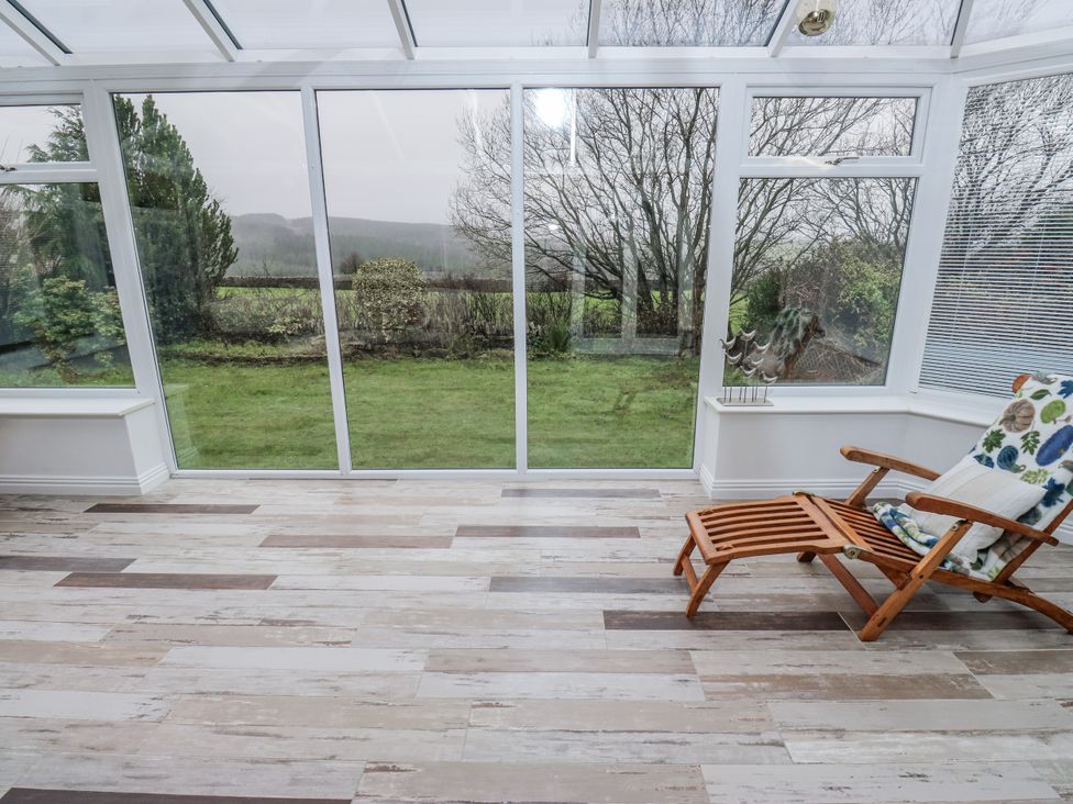 A conservatory with a chair and large windows at The Peak View Holmfirth