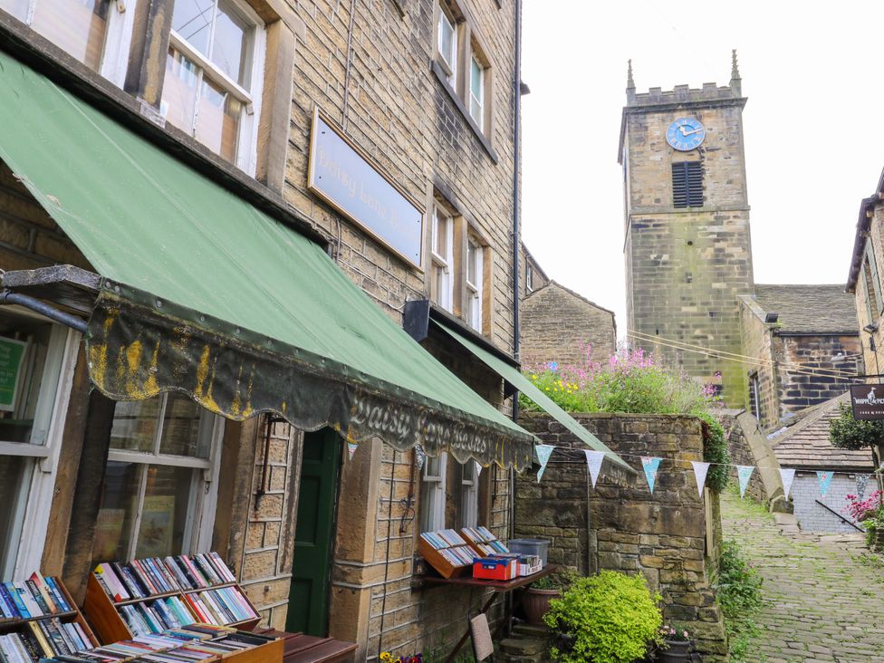 An outdoor view of a building with books outside and a church tower in The Peak View Holmfirth Hade Edge Yorkshire