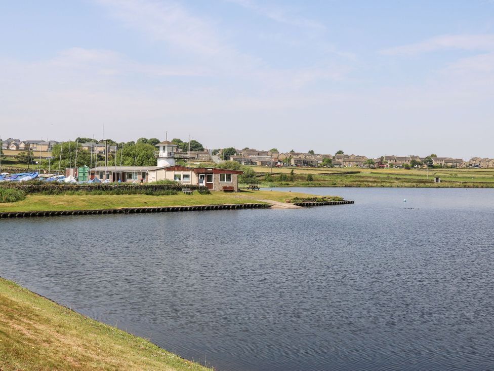 A lake with a building and boats nearby at The Peak View Holmfirth Hade Edge, Yorkshire
