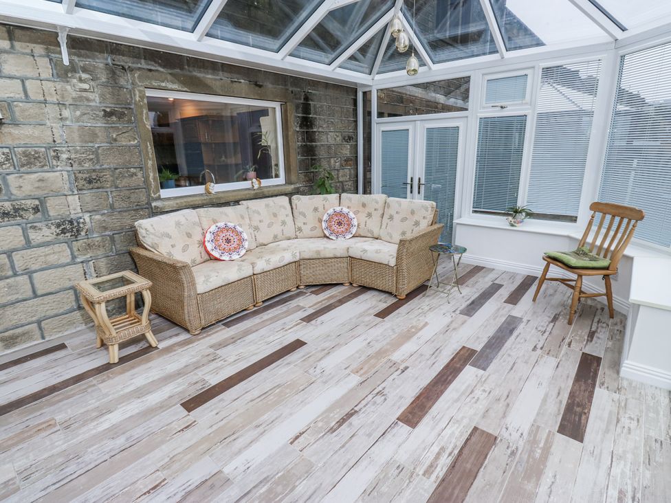 A conservatory with a sofa and side table at The Peak View Holmfirth, Hade Edge, Yorkshire