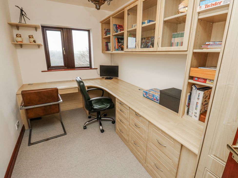 An office with a desk, computer monitor, and shelves at The Peak View Holmfirth in Hade Edge, Yorkshire