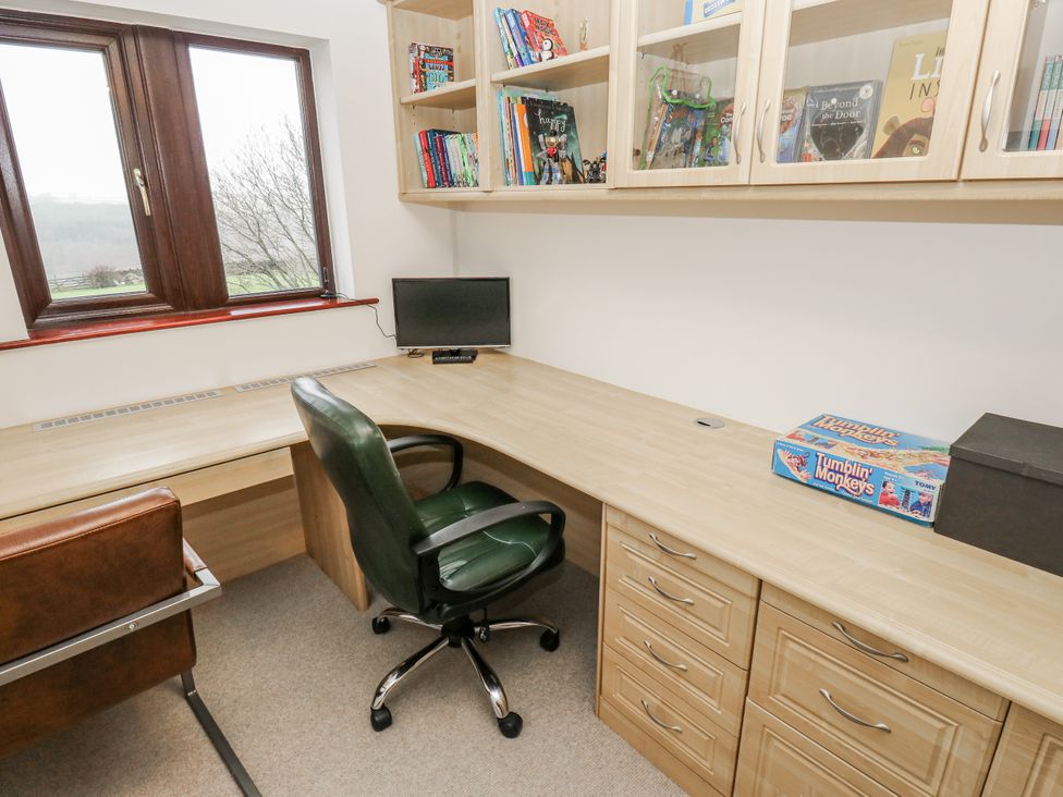 An office with a desk, chair, computer monitor, and bookshelf at The Peak View Holmfirth in Hade Edge, Yorkshire