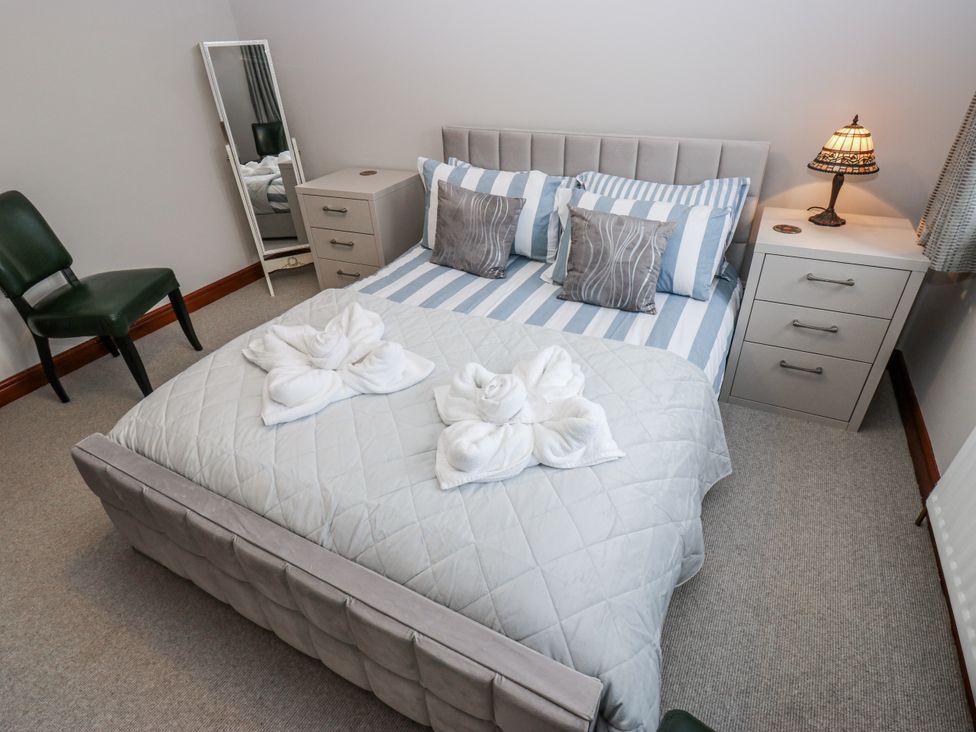 A bedroom with a bed, nightstand, mirror, and a chair at The Peak View Holmfirth in Hade Edge, Yorkshire