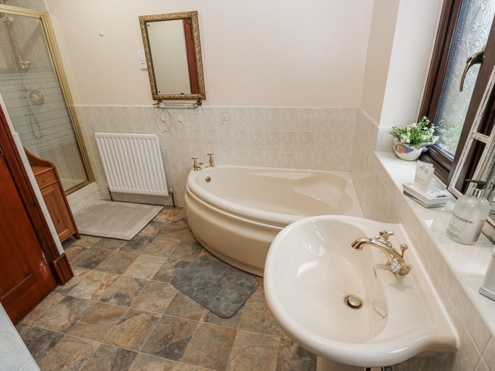 A bathroom featuring a bathtub, shower, sink, and mirror at The Peak View Holmfirth, Hade Edge, Yorkshire