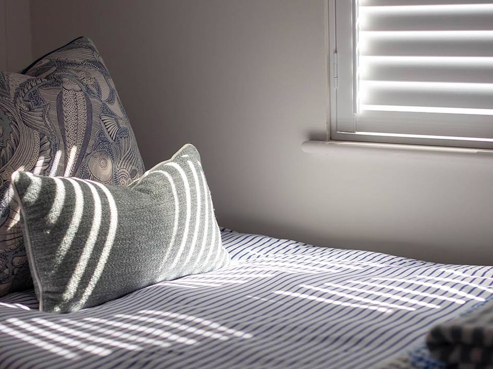 A bed with striped bedding and pillows at Wood Cottage 