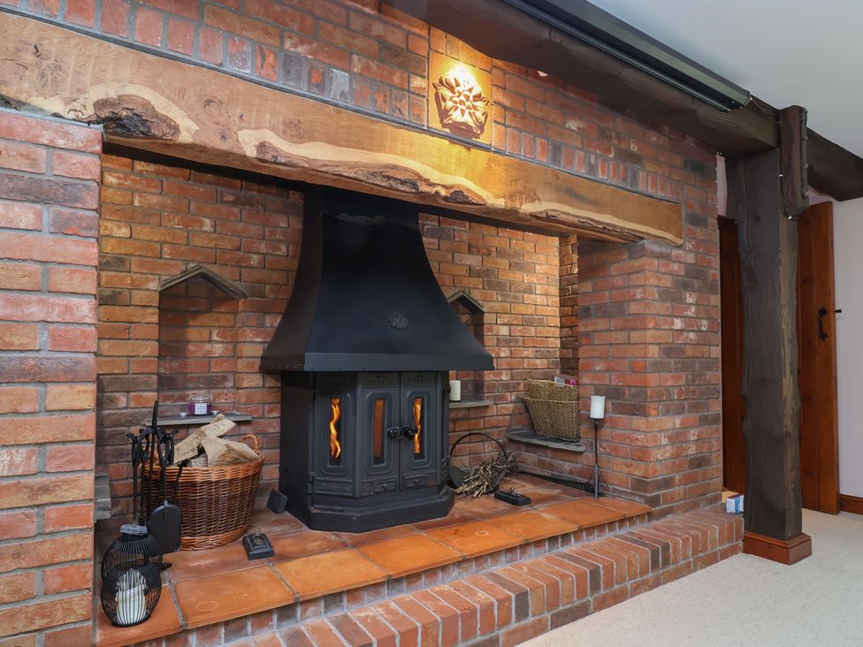 A fireplace with a wood stove and brick wall at Hedgerose Goodleigh near Barnstaple