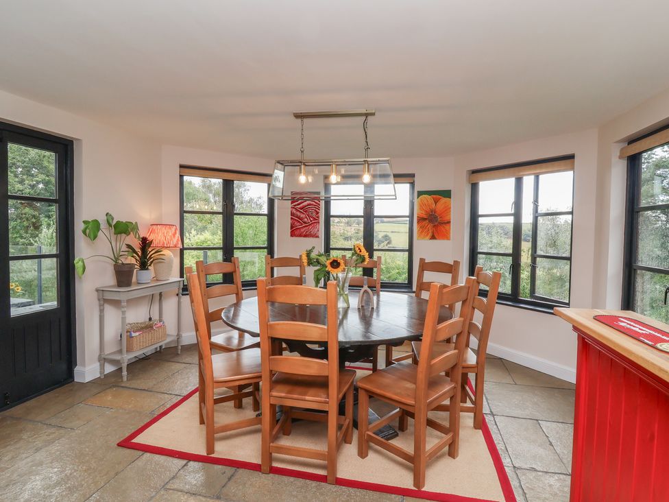 A dining room with a round table and eight chairs at Hedgerose in Goodleigh near Barnstaple