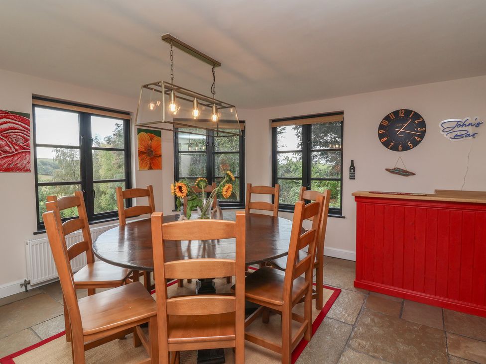 A dining room with a round table and chairs at Hedgerose in Goodleigh near Barnstaple