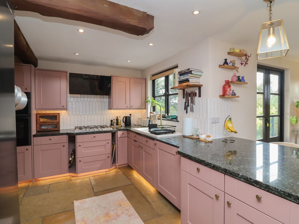 A kitchen with pink cabinets and a granite countertop at Hedgerose in Goodleigh near Barnstaple